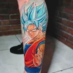 Фото татуировки Гоку из аниме Dragon Ball на ноге. Яркий и красочный рисунок в стиле аниме. Эскиз тату для фанатов аниме.