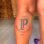 Фото тату: простая татуировка с большой буквой "P", инициалами "S.E.P" и датой "1914" на икре ноги. Минималистичный дизайн с тонкими линиями.