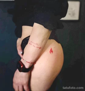 Фото тату на руке с изображением маленького пламени и надписи 'the romantic, but she dirty'. Черные чернила, минималистичный стиль. Идеи для тату.