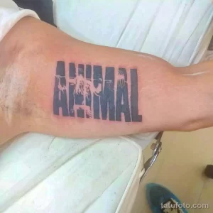 Фото тату: татуировка надписи "ANIMAL" большими буквами на руке. Текстовая татуировка, простой дизайн, черно-белый рисунок.