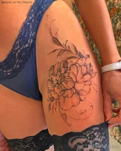 Фото тату: Один большой пион, выполненный в технике dotwork, с добавлением листьев и стеблей. Татуировка расположена на бедре.