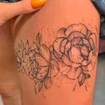 Фото тату: Два больших пиона, выполненных в технике dotwork, с множеством точек, создающих эффект затенения. Татуировка расположена на бедре.