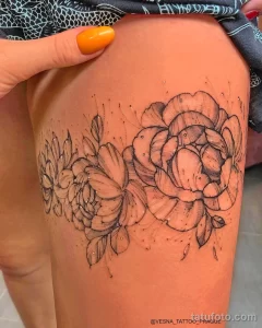 Фото тату: Два больших пиона, выполненных в технике dotwork, с множеством точек, создающих эффект затенения. Татуировка расположена на бедре.
