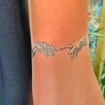 Фото тату: Изображение двух рук, одна из которых геометрическая, а другая реалистичная, тянутся друг к другу. Татуировка выполнена в черных чернилах.