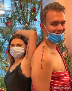 Фото тату: Пара в медицинских масках демонстрирует татуировки с надписями на внутренней стороне предплечий. Надписи выполнены черными чернилами.