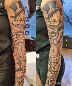 Фото тату на руке с изображением персонажей Looney Tunes, денег и игральных костей. Яркий и детализированный рисунок в мультяшном стиле.