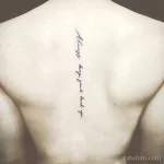 Фото тату: черная надпись 'Always keep your head up' вертикально вдоль позвоночника на спине мужчины. Минималистичный дизайн.