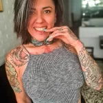 Фотография яркой девушки с множеством татуировок на теле. Девушка с пирсингом и стильным образом.