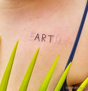 Минималистичная татуировка надписью 'EARTH' на груди молодой женщины. Простые линии, нежные цвета, современный стиль.