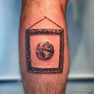 Фото тату: татуировка в технике dotwork с изображением Земли в старинной рамке, висящей на цепочке.