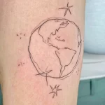 Фото минималистичной татуировки Земли с двумя звездами на ноге. Рисунок выполнен тонкими черными линиями.