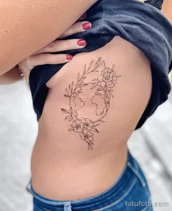Фото тату: Линейный рисунок земного шара, окруженного нежными цветами, на боку.