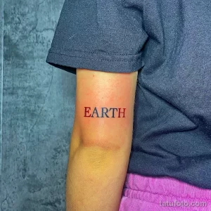 Фото тату с надписью 'EARTH' красным цветом на предплечье. Простой и лаконичный дизайн, минималистичный рисунок татуировки.