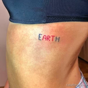 Фото тату с надписью "EARTH" на боку. Минималистичный рисунок татуировки в красном цвете, символизирующий любовь к планете.