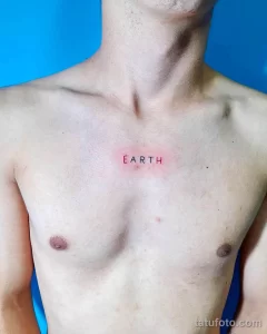 Фото тату на груди: минималистичная надпись 'EARTH' красным цветом. Простой и лаконичный рисунок татуировки.