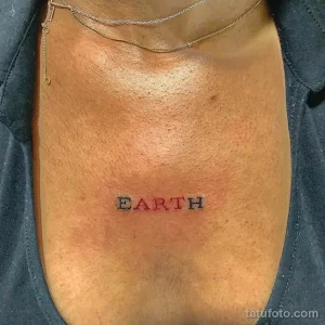 Фото простой татуировки надписью 'EARTH' на груди, выполненной черными чернилами в минималистичном стиле.
