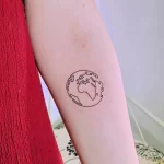 Фото тату с изображением контура Земли, выполненное в технике тонких линий на предплечье.
