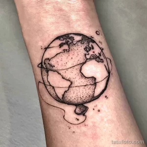Фото тату: милая татуировка Земли, выполненная в технике dotwork с использованием точек и штрихов, на предплечье. Подходит для любителей минимализма и космоса.