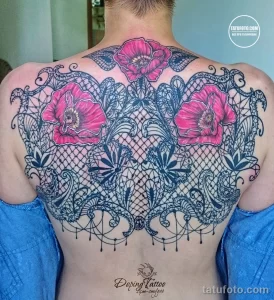 Фото тату на спине с изображением ярких маков, обрамленных изящным кружевом. Черно-серый рисунок татуировки.