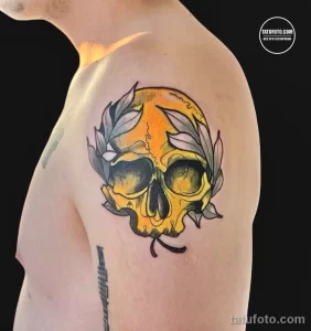 Фото тату: красочная татуировка черепа, окруженного цветами и листьями. Рисунок татуировки выполнен в стиле олдскул с яркими цветами.