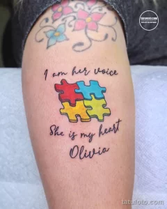Фото тату на плече с изображением пазлов и надписью 'I am her voice, She is my heart Olivia', выполненное в цветном стиле.