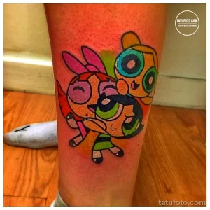 Фото тату Powerpuff Girls на ноге, выполненное в ярких и насыщенных цветах. Детализированное изображение трех супергероинь в динамичной позе.