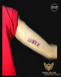 Фото тату: надпись "LOSER" (Неудачник) на руке, выполненная в стиле граффити с использованием ярких цветов. Смелый и провокационный эскиз.