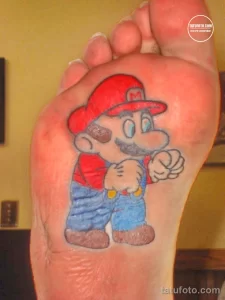 Фото татуировки Марио на стопе. Яркий и мультяшный рисунок персонажа из игры Super Mario. Забавная и оригинальная татуировка.