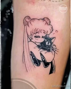 Фото тату на руке: изображение Sailor Moon, держащей в руках черную кошку. Яркий и красочный рисунок татуировки.