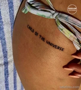 Фото тату на боку: минималистичная надпись "Child of the Universe" черным цветом, выполненная простым шрифтом.