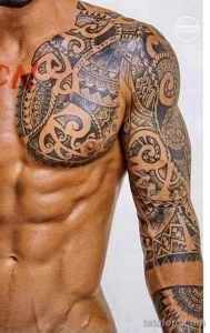 Фото тату на теле: сложный полинезийский узор, покрывающий грудь и руки, выполненный в черном цвете с использованием геометрических фигур и спиралей.