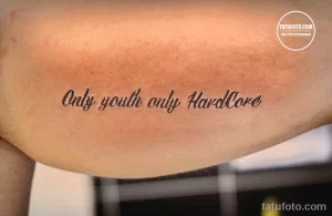 Фото тату на груди: надпись 'Only youth only HardCore' черным цветом. Минималистичный стиль, лаконичный дизайн, короткая фраза.