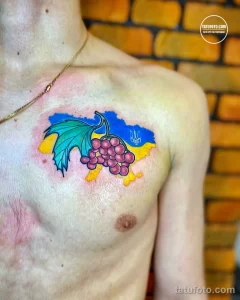 Фото тату на груди с изображением карты Украины, виноградной лозы и украинской символики. Рисунок выполнен в ярких цветах.