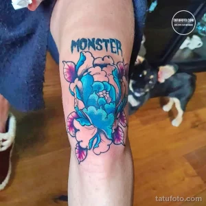 Фото тату на руке: большой цветок пиона в ярких цветах с надписью "MONSTER". Стильный и оригинальный рисунок татуировки.