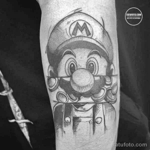 Фото тату с изображением Марио из игры Super Mario Bros. на руке. Рисунок выполнен в мультяшном стиле.