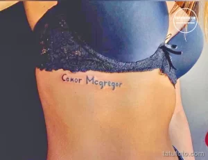 Фото тату: надпись "Conor McGregor" выполненная простым шрифтом на боку. Небольшая татуировка для поклонников MMA.