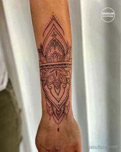 Фото тату: сложный узор мандалы, выполненный в технике blackwork на предплечье. Детализированный эскиз тату с геометрическими элементами.