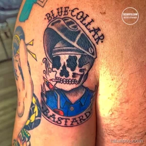 Фото тату в стиле олд скул: череп в морской шапке с надписью 'Blue Collar Bastard'. Яркие цвета и четкие контуры на руке.