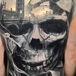 Фотография масштабной татуировки на спине, изображающей череп на фоне Биг Бена и разрушающегося здания. Татуировка выполнена в реалистичном стиле.