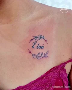 Фото тату: небольшая татуировка с именем "Eloá" и ветками с цветами, выполненная на ключице.