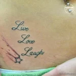 Фото тату надписи 'Live, Love, Laugh' на боку. Черно-красная татуировка с небольшим изображением звезды. Изящный шрифт и минималистичный дизайн.