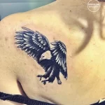 Фото тату с изображением летящего орла на груди. Черно-белый рисунок с четкими линиями и детализацией.