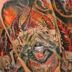 Фото тату: детализированная татуировка скорпиона, обвивающего череп, с яркими красными и черными акцентами на теле.