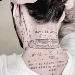 Фото тату на шее с изображением древнеегипетских символов, крыльев и текста. Черно-белое изображение.
