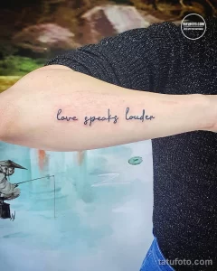 Фото тату: минималистичная надпись "Love speaks louder" на руке, выполненная тонкой линией.