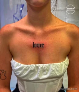 Фото татуировки надписи 'lover' на груди. Черная готическая надпись с изящными буквами, расположенная под ключицами.