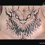 Фото тату дракона на груди. Черно-белый рисунок с острыми зубами и когтями, создающий мрачный и мистический образ.