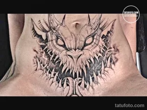 Фото тату дракона на груди. Черно-белый рисунок с острыми зубами и когтями, создающий мрачный и мистический образ.