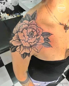 Фото тату: Крупная татуировка розы на плече, выполненная в технике blackwork. Использование только черных чернил и различных оттенков серого.