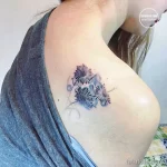 Фото тату: акварельные одуванчики на плече. Нежные голубые и серые оттенки, реалистичное изображение пушистых головок одуванчиков.